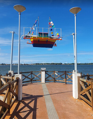 Barco colorido  no Museu da Gente Sergipana, com vista para o rio e céu azul.